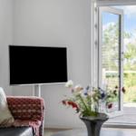 A living room with a TV, sofa, and view of the terrace.