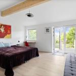 Bedroom with bed, bench, and balcony door. Visible wooden beam and wall art.