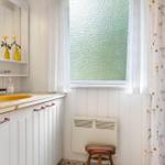 Bad mit Waschbecken, Spiegelschrank und Fenster mit Glastüren.