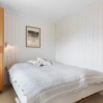 Schlafzimmer mit Bett, Kleiderschrank und Wandbild.
