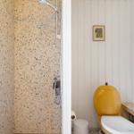 Bad mit Dusche, gelbem WC und floraler Duschvorhang.