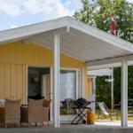 Terrasse mit Grill, Tischen und Stühlen unter weißem Dach. Daneben steht eine Liegestuhl.