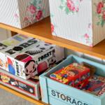 Holzregal mit Spielzeugboxen und floralen Aufbewahrungskisten.