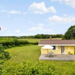 Gelbes Haus mit Terrasse, weißem Sonnenschirm und Garten. Daneben steht eine dänische Flagge.
