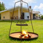 Feuerkessel mit hängendem Grillrost auf Rasen vor Ferienhaus