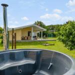 Hütte mit Whirlpool und Terrasse im Grün. Dänische Flagge weht.