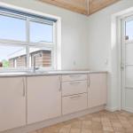 Küche mit Arbeitsplatte, Spüle und Fenster. Tür führt nach draußen.
