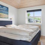 Schlafzimmer mit Bett, Wandbild und Fenster. Holzdecke und hellbrauner Boden.