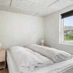 Schlafzimmer mit Bett, zwei Nachttischen und Fenster mit Blick auf Grün.