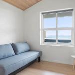 Ein Raum mit einem grauen Sofa, einem Fenster mit Blick auf Wasser und einem kleinen Tisch mit Pflanzen.