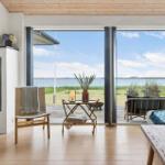 Wohnraum mit Kamin, Sitzgelegenheiten und Blick auf Wasser und Gras.