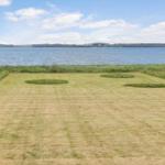 Grüner Rasenbereich mit drei runden Grasflächen am Wasser.