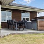 Terrasse mit Tisch, Stühlen und Whirlpool. Holzwand und Fenster sichtbar.