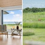 Ein Raum mit Kamin und Blick auf Wasser. Ein Hirsch im Gras am Ufer.