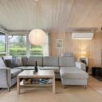 Wohnzimmer mit Sofa, Kamin und großen Fenstern.