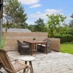 Terrasse mit Holztisch, Stühlen und Gartenansicht.