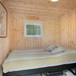Schlafzimmer mit Holzwand, Bett und Fenster. Wandbild und Hängematte sichtbar.