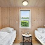 Zwei Betten in einem Holzraum mit Fenster und Tisch.