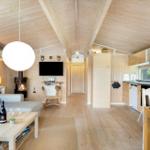 Wohnung mit Holzdecke, Kamin, Sofa, TV und Küche.