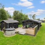 Schwarze Hütte mit Terrasse, Whirlpool und Garten. Blick auf den Himmel.