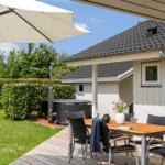 Deck with table, chairs, and umbrella. Backyard with hot tub and lawn.