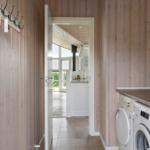 House with wooden walls, washing machine, and view into the kitchen.