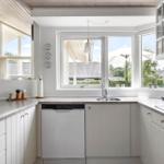 Kitchen with white cabinets, countertop, and garden view through windows