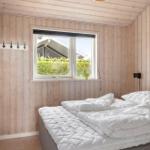 Bedroom with wooden walls, window, and bed with white bedding.