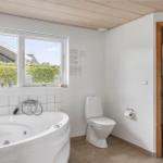 Bathroom with bathtub, toilet, and window overlooking the garden.