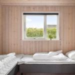 Bedroom with two mattresses, wooden walls, and view of greenery through window.