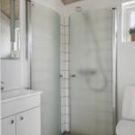 Bathroom with shower, sink, and toilet. Window with plant.