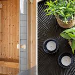 Sauna with wooden wall and bench. Table with plants and candles.