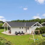 House with terrace, loungers, swing, and trampoline on a green lawn.