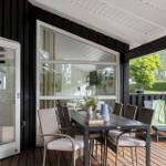 Deck with dining table, chairs, and loungers. Door and large window to interior.