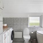 Bathroom with bathtub, toilet, washing machine, and windows with frosted glass.