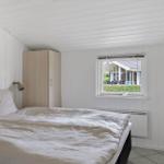 Bedroom with bed, wardrobe, and view of garden through window.
