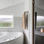 Bath with whirlpool, frosted glass window, and wooden door.
