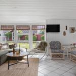 Living room with sofa, chairs, and TV. Windows overlook the garden.