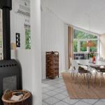 Dining area with table, chairs, and window. Next to it stands a wood stove.