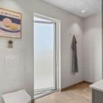 Badezimmer mit Toilette, Spiegel und Dusche. An der Wand hängt ein Bild mit Zitronenmotiv.