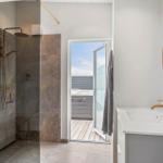 Dusche mit Glaswand, Waschbecken und Blick auf die Terrasse mit Whirlpool.
