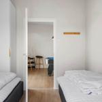 Zwei Schlafzimmer mit Matratzen und weißen Bettdecken. Durchgang zu einem Raum mit Tisch und Stühlen.