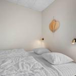 Schlafzimmer mit Bett, Wandlampe und Herzdekoration. Blick auf Balkon.