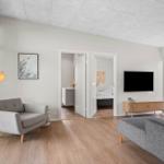 Wohnraum mit Sofa, Sessel, Fernseher und Blick auf den Garten.