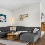 Ein Wohnzimmer mit grauem Sofa, Holztisch und Wandbildern.