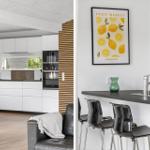 Modern kitchen with white cabinets and kitchen island. Bar stools and wall art are visible.