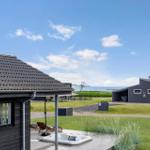 House with hot tub, garden, and sea view under blue sky.