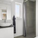 Bathroom with sink, mirror, shower, and window.
