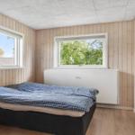 Bedroom with bed, two windows, and wall-mounted TV.
