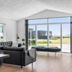 Living room with black leather sofa, wooden floor, and large windows for views.